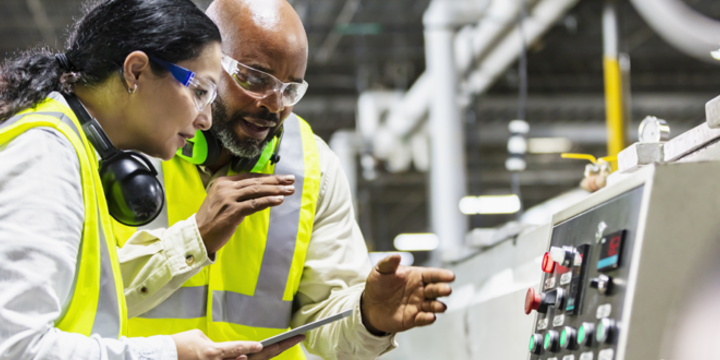 Multiracial workers in factory at machine control panel