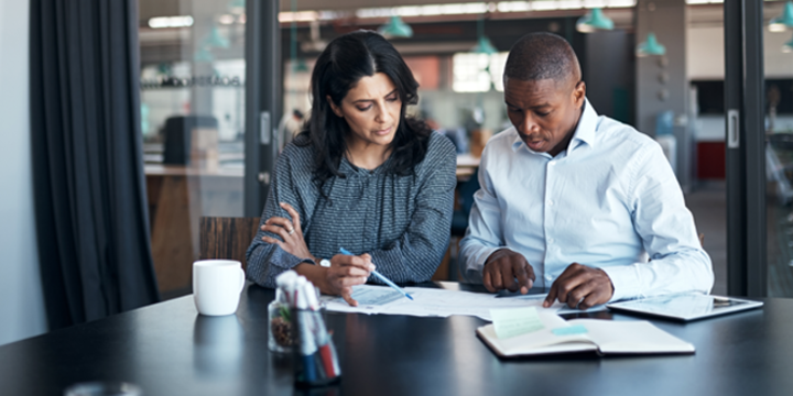 Businessman and businesswoman going over paperwork in a modern office