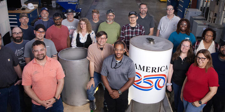 A group of people around a cylindrical time capsule