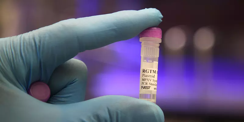 A gloved hand is holding up a small plastic vial labeled "RGTM plasmid."