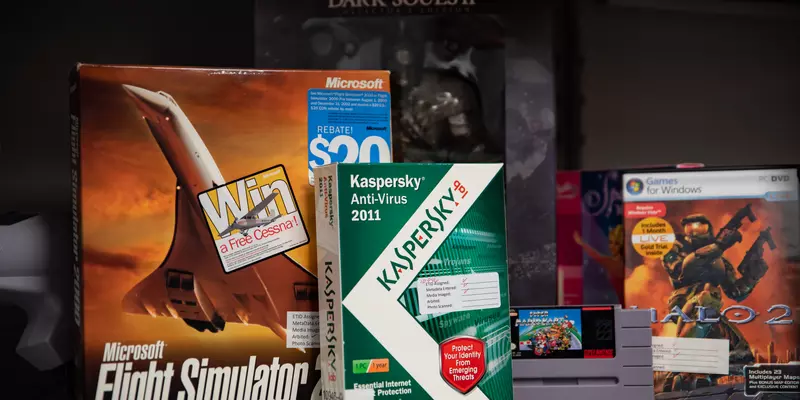 Boxes of old software stand on a shelf, inlcuding a flight simulator, Dark Souls II and a Kaspersky anti-virus product.