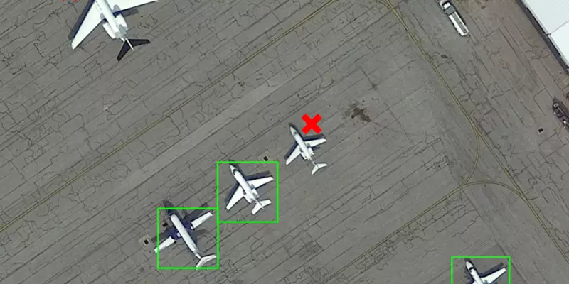 Multiple airplanes on the tarmac. Some are surrounded by a green box and others by a red X.