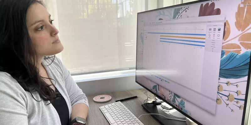 Carina Hahn sits at a workstation and looks at a computer screen.