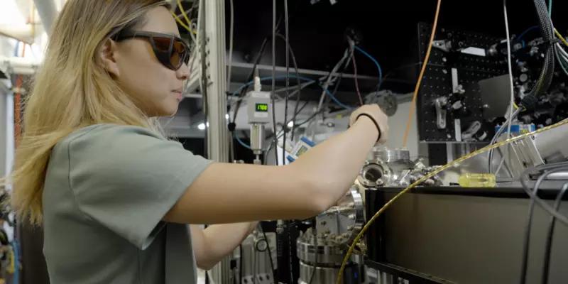 Sun Park wears safety glasses as she adjusts wiring and equipment in the lab. 