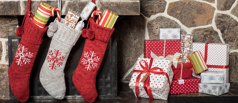 stockings stuffed with gifts hung on a fireplace mantle with wrapped presents