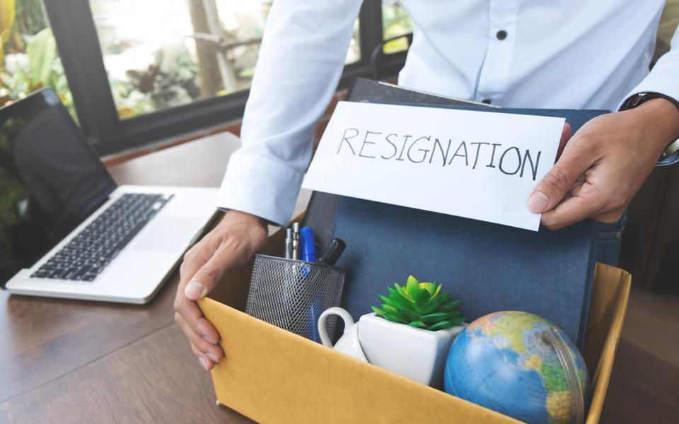 Employee holding a resignation letter with a box of their belongings.