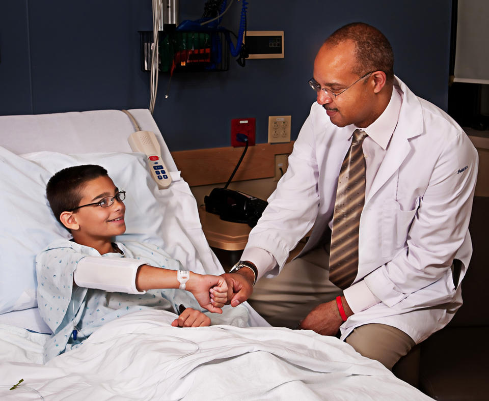 AtlantiCare photo of doctor checking on young patient in hosptial bed.