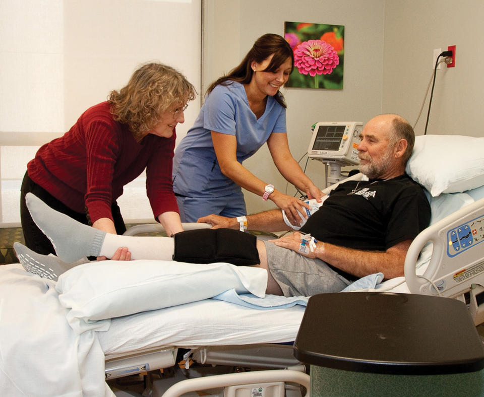 Hill Country Memorial photo of two nurses taking care of a patient in hospital bed.