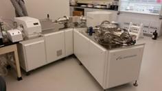Photograph of laboratory instrument consisting of modular cabinets, vacuum chambers, and plasma chamber. 