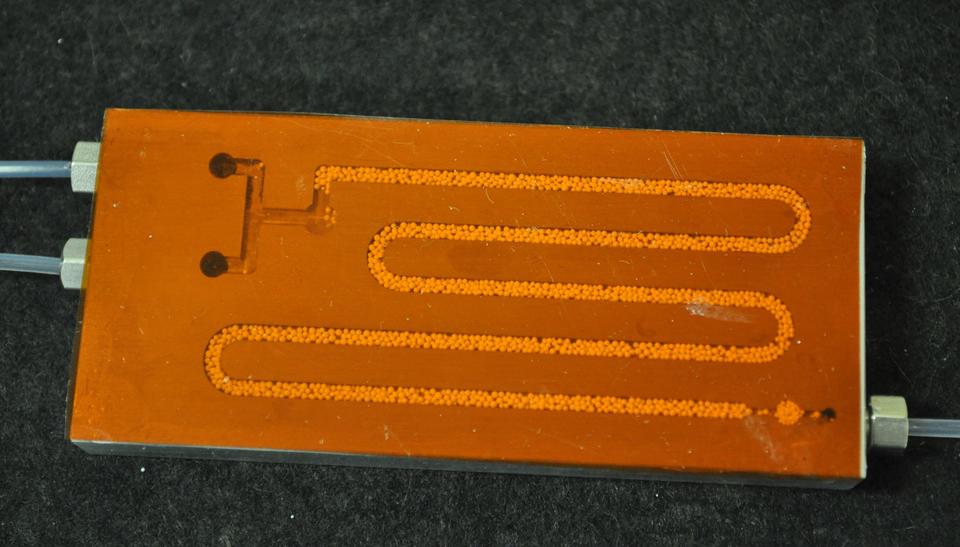 Typical NIST microreactor plate for studying enzyme catalyzed polymerization. The aluminum plate, topped with a transparent film, is approximately 40 mm by 90 mm centimeters.