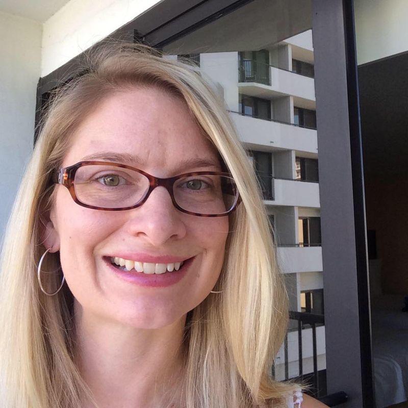 Amanda Forster, a person with long blonde hair and glasses, smiling. 