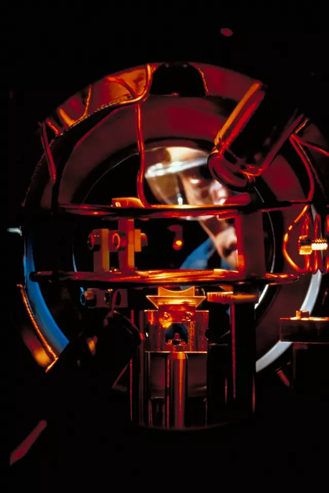 Researcher Kris Helmerson observes a tiny glowing cloud of sodium atoms caught by six intersecting laser beams in a vacuum chamber. 