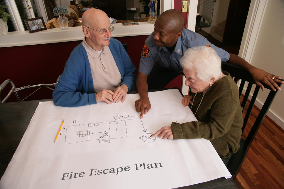 Three people looking at drawing of Fire Escape Plan