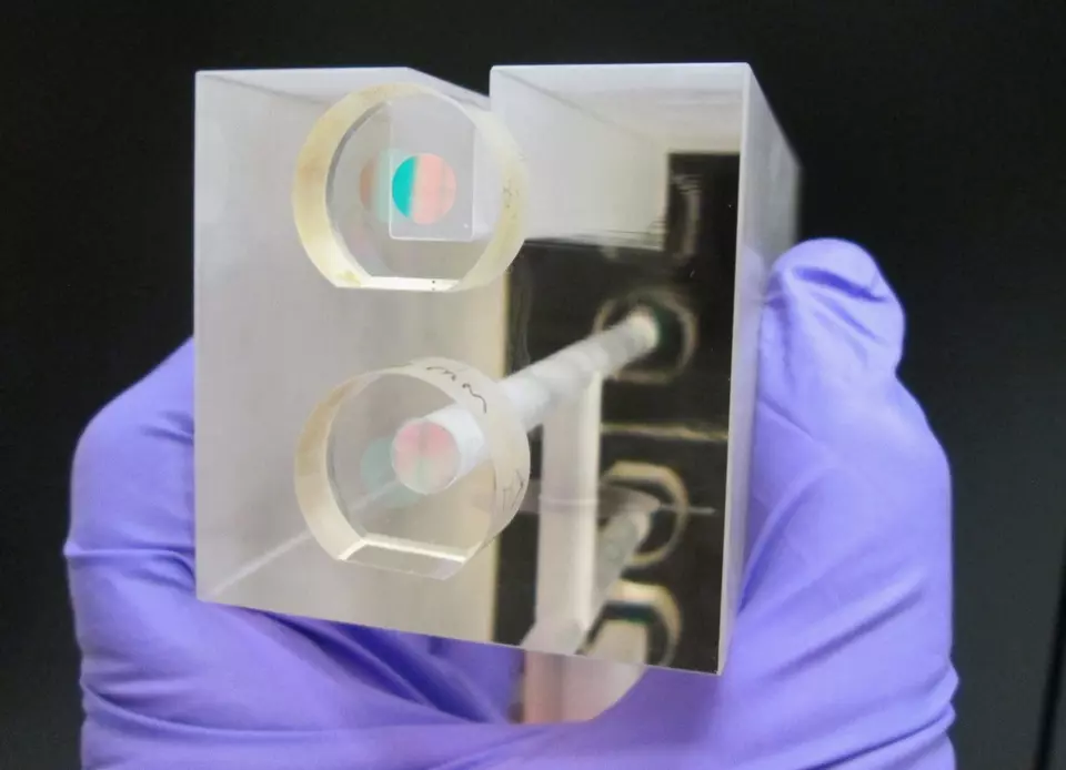A NIST researcher holds a fixed length optical cavity (FLOC), a structure that enables highly accurate, quantum-based measurements of &nbsp;pressure.