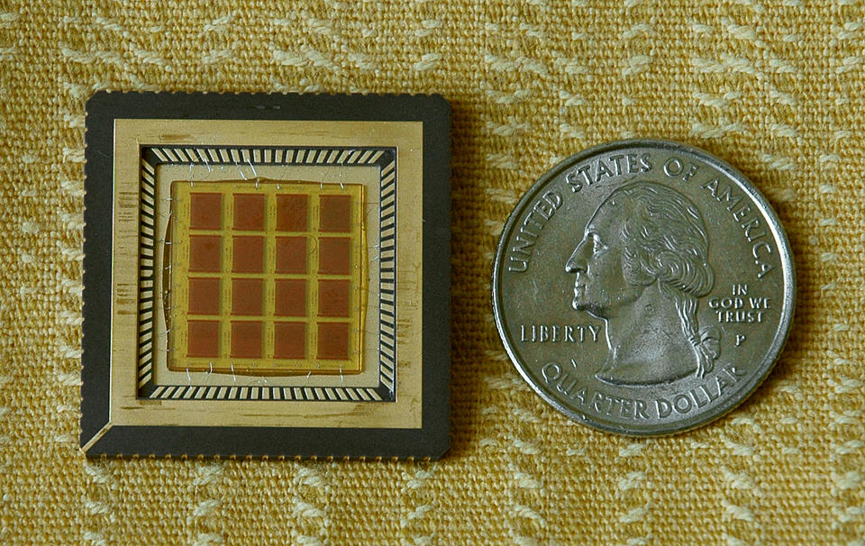 A glass microchip next to a quarter showing that the two are approximately the same size