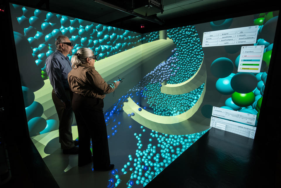 Researchers wearing virtual reality headsets in the CAVE, with concrete particles on display