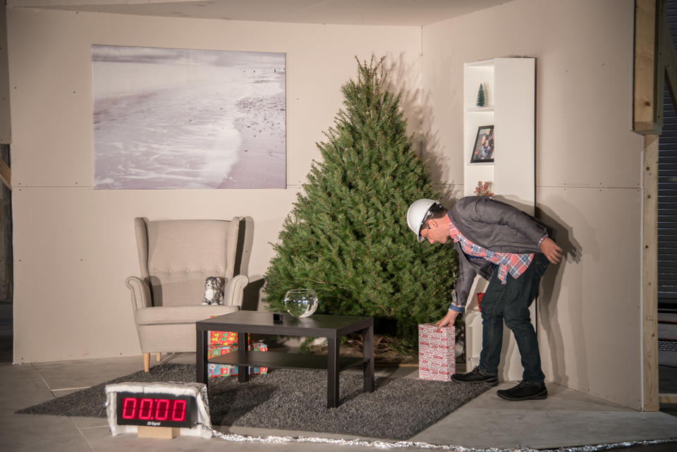 NIST employee places a Christmas present under an undecorated Christmas tree