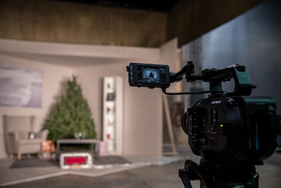 Video camera aimed at a room with a Christmas tree, bookshelf, coffee table and chair