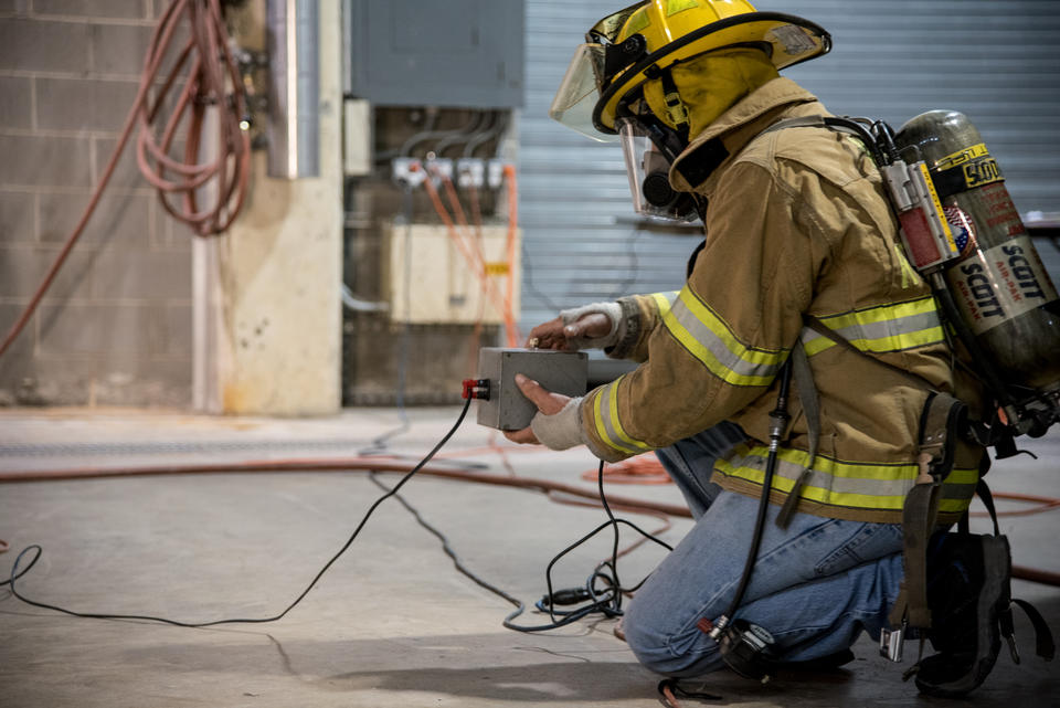 NIST scientist pushes a button to ignite the dry Christmas tree