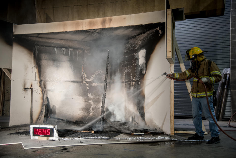 NIST employee spraying water to put out a fire