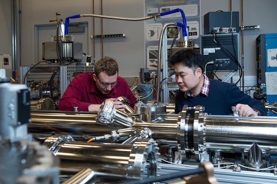 Two men work on a microscope