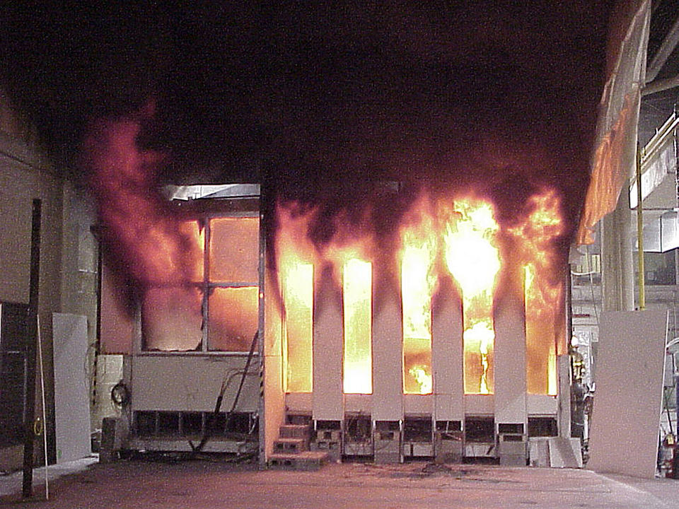 Color photo of white structure meant to replicate and office on fire. 