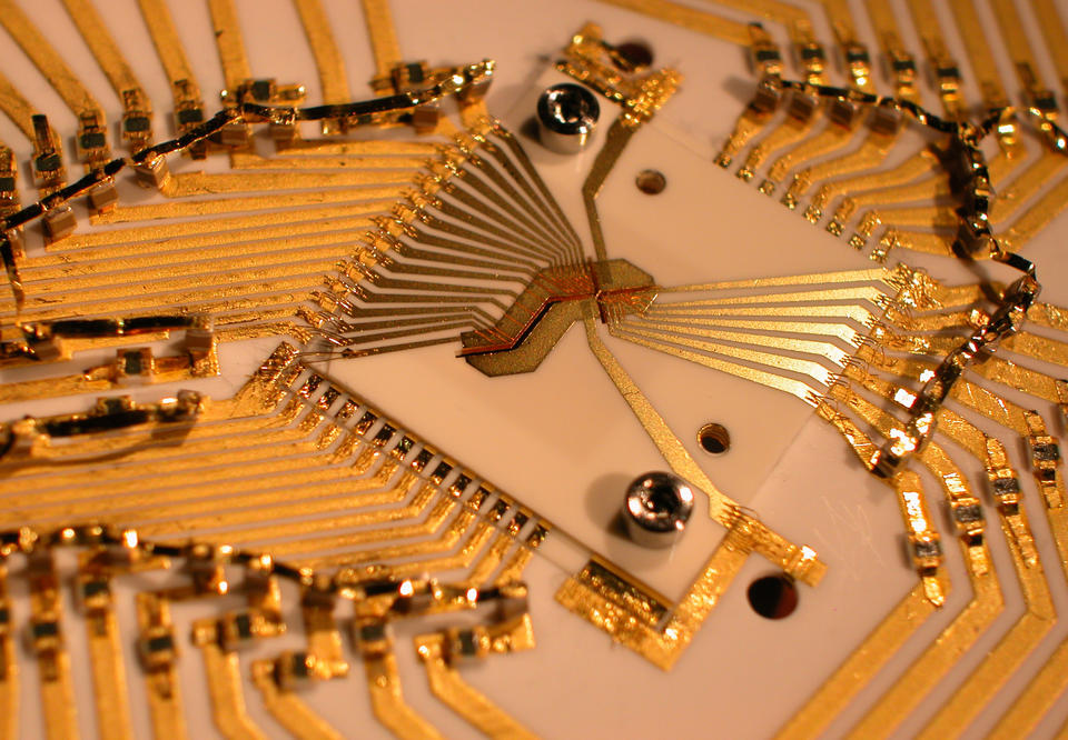 Square device surrounded by a design of gold wiring.