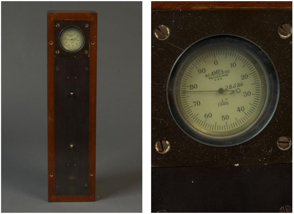 A long, thin, rectangular wooden box framing a metal plate with an circular analog gauge reading from 1 to 100. Printed on the gauge are the name "B.C. Ames Co., Waltham, Mass. U.S.A," and "1"/1000," and a handwritten "28586 B."