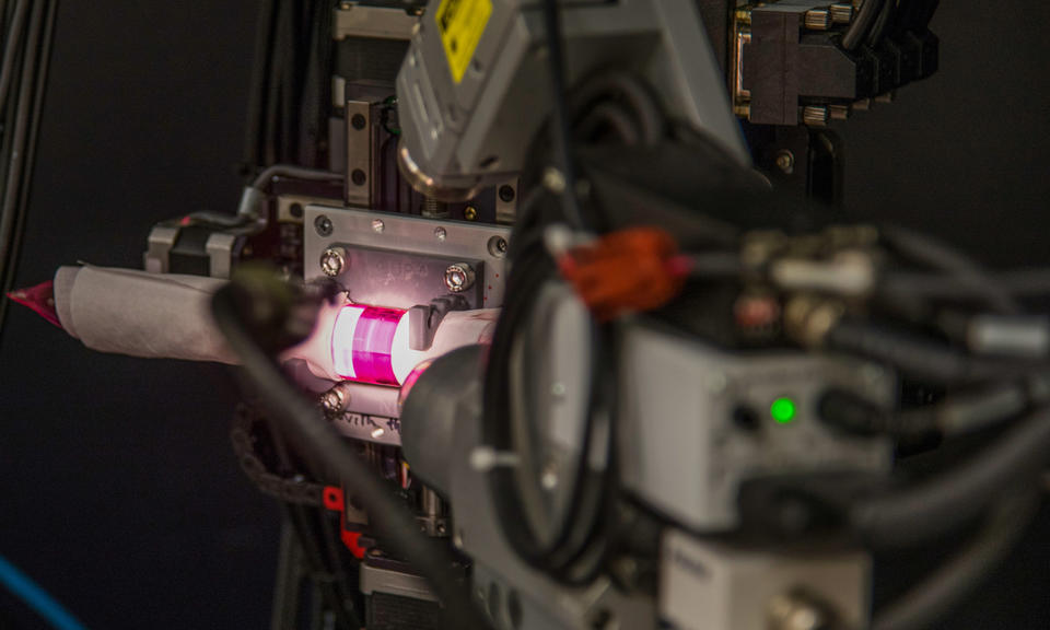 A ruby colored rod, wrapped in tissue paper and illuminated by a bright light, mounted inside an X-ray diffraction machine