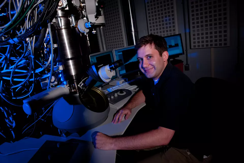 Ryan M. White sitting next to a microscope