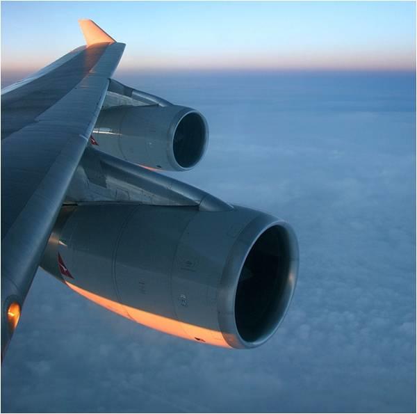 Closeup of a plane's jet engine as it flies above the clouds.