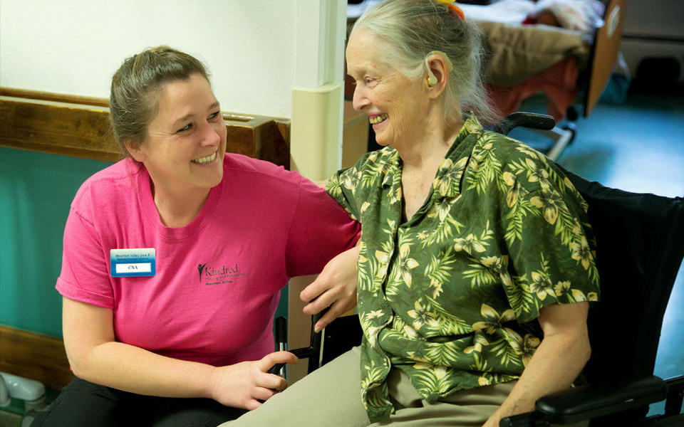 Photo of Kindred Nursing and Rehabilitation Center – Mountain Valley of Cascadia employee helping a patient in a wheelchair.