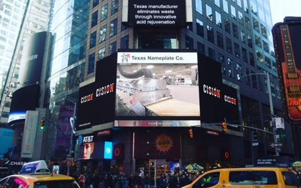 Texas Nameplate Company billboard in New York City. The caption reads "Texas manufacturer eliminates waste through innovative acid rejuvenation."