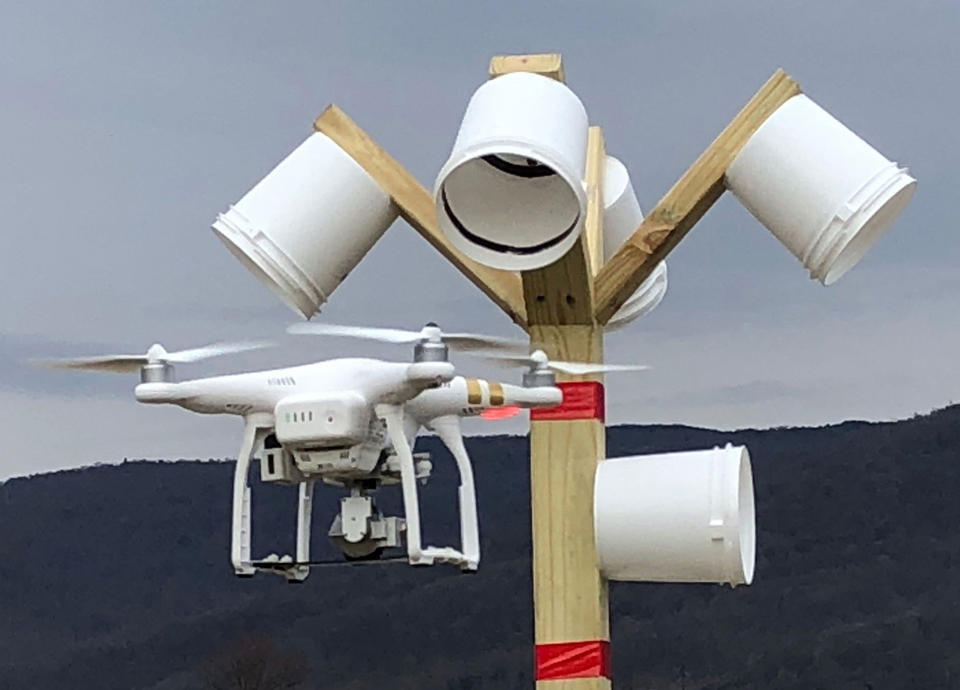 A drone in flight approaches a bucket-shaped target attached to a pole during an evaluation on the NIST performance test course.