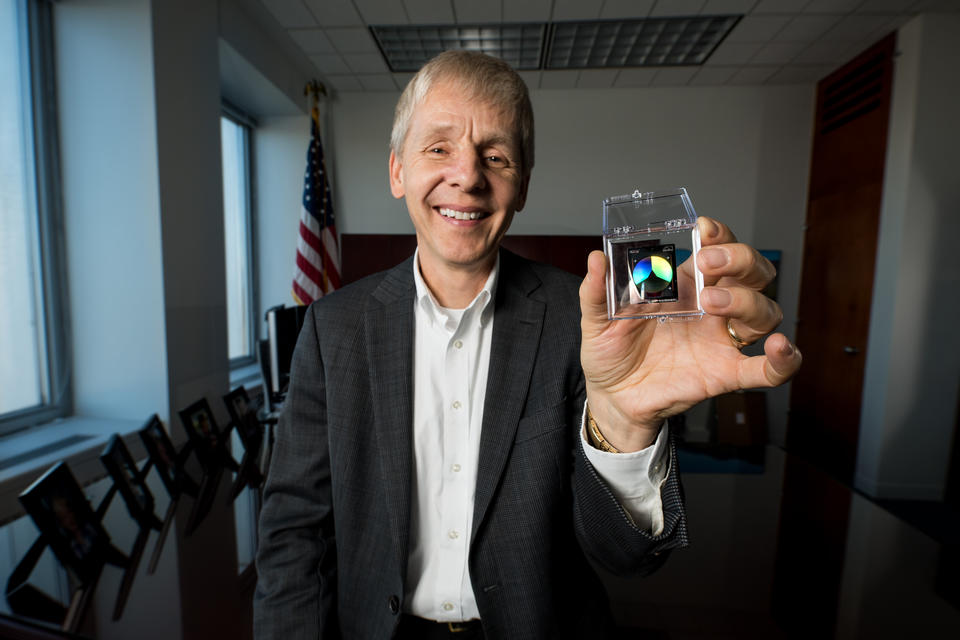 Man holding a NIST on a Chip device