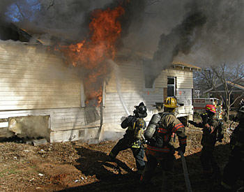 House burning. Firefighters are using a host to douse the flames.