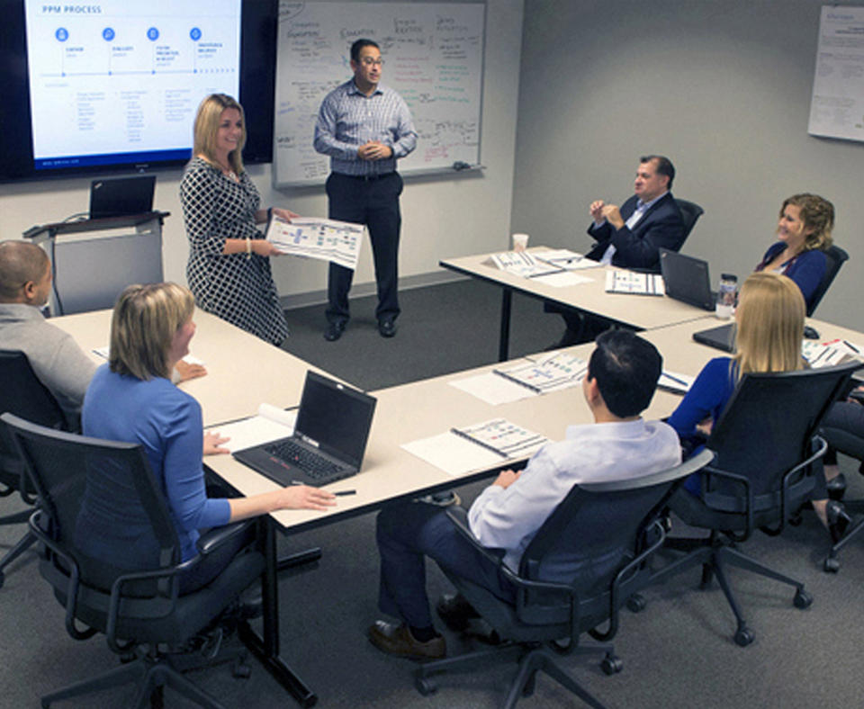 IPMC photo showing a group of people sitting in a meeting watching a presentation.