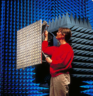 A scientist stands near an antenna in the anechoic chamber