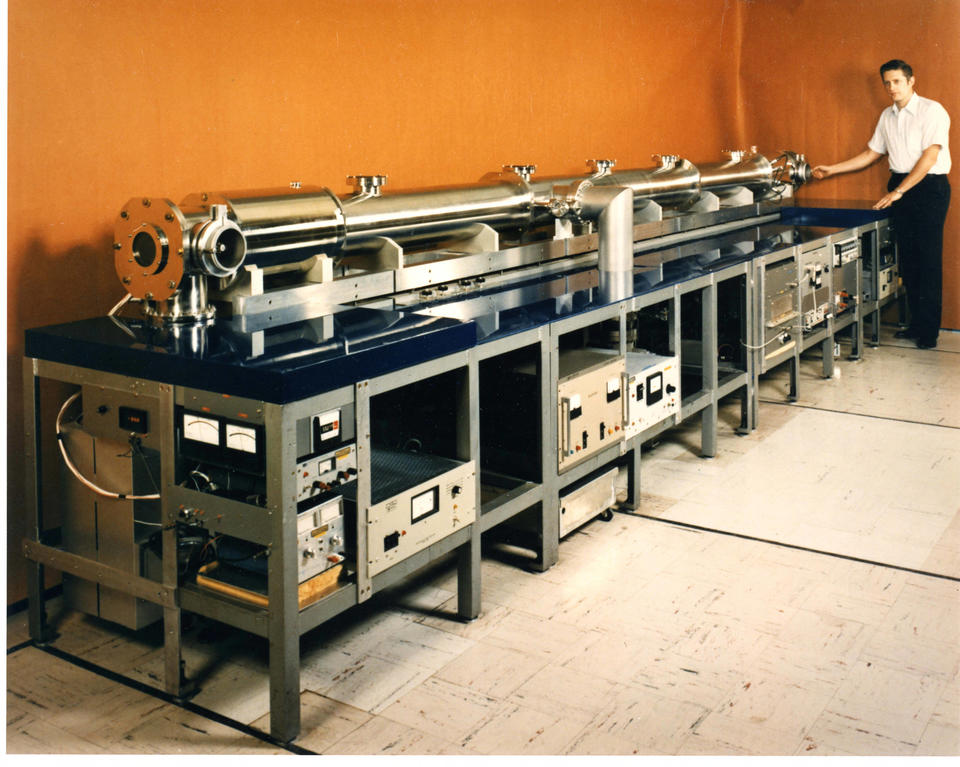 Long metal cylinder on a table with a man standing at the far end.