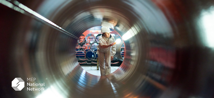 person quality inspecting a large metal pipe