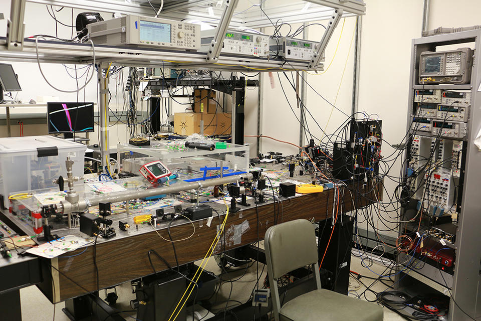 picture of a physics lab strewn with wires with a laser table