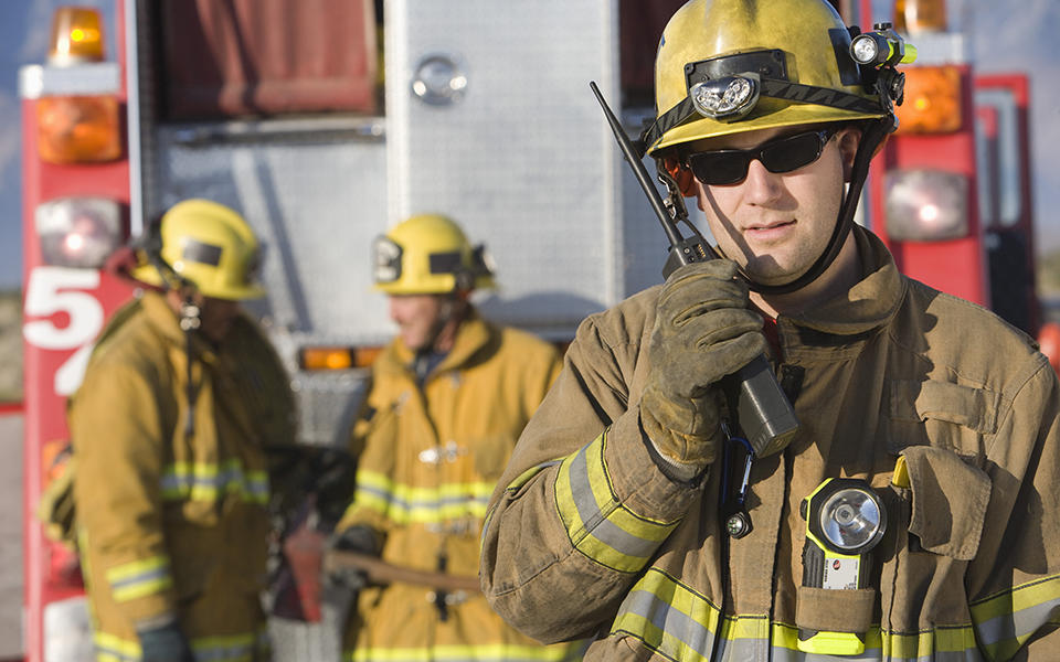 firefighter speaks into a handheld radio