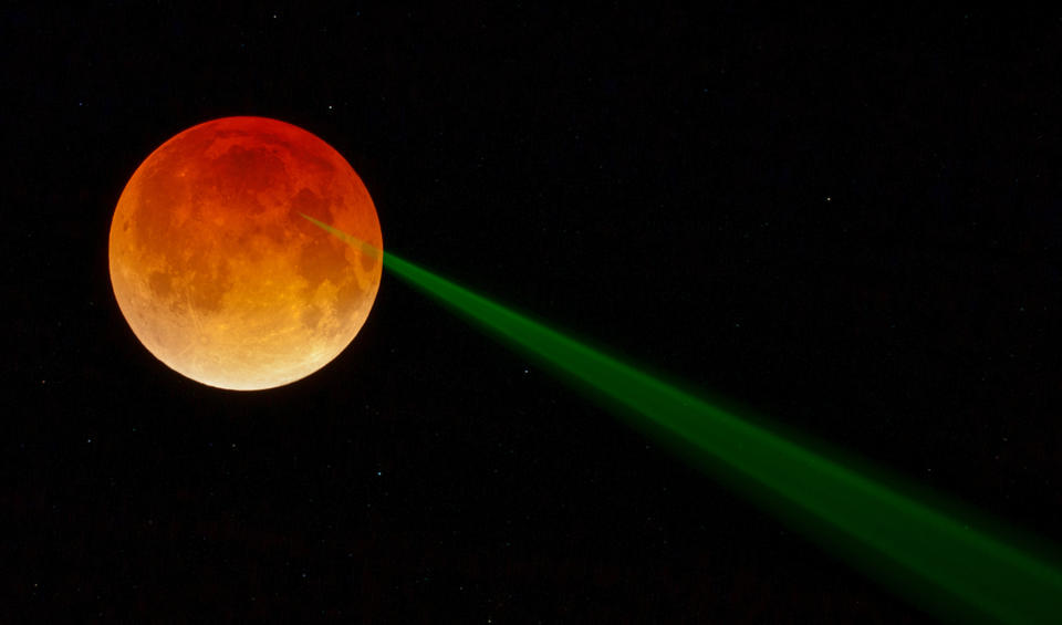 Orange moon with a laser beam being shot at it