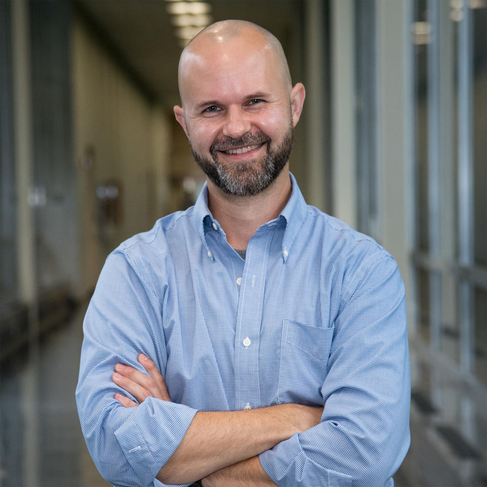 Portrait of Jason Stoughton standing in a hallway.