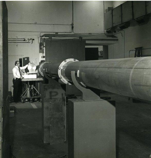 A man stands in the far background at the end of a long metal tube