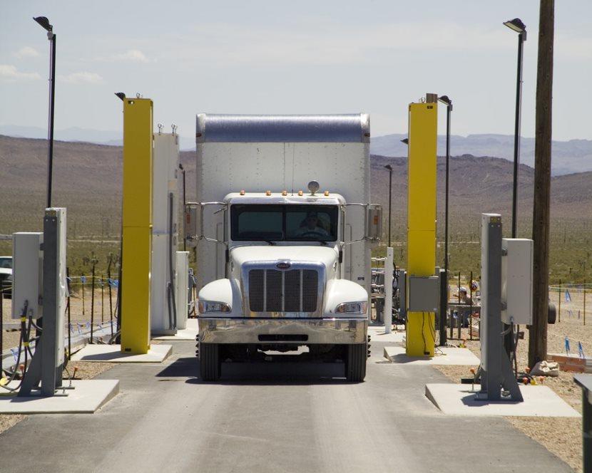 A semi truck shown head-on between tall yellow detectors