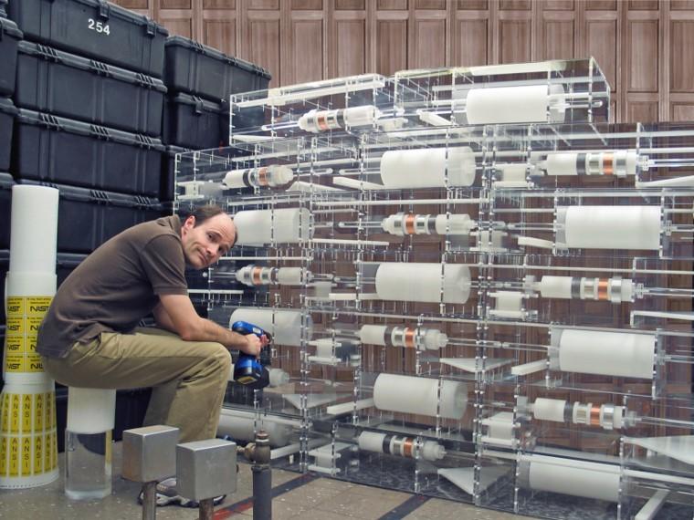 A man sits in front of a series of clear cases