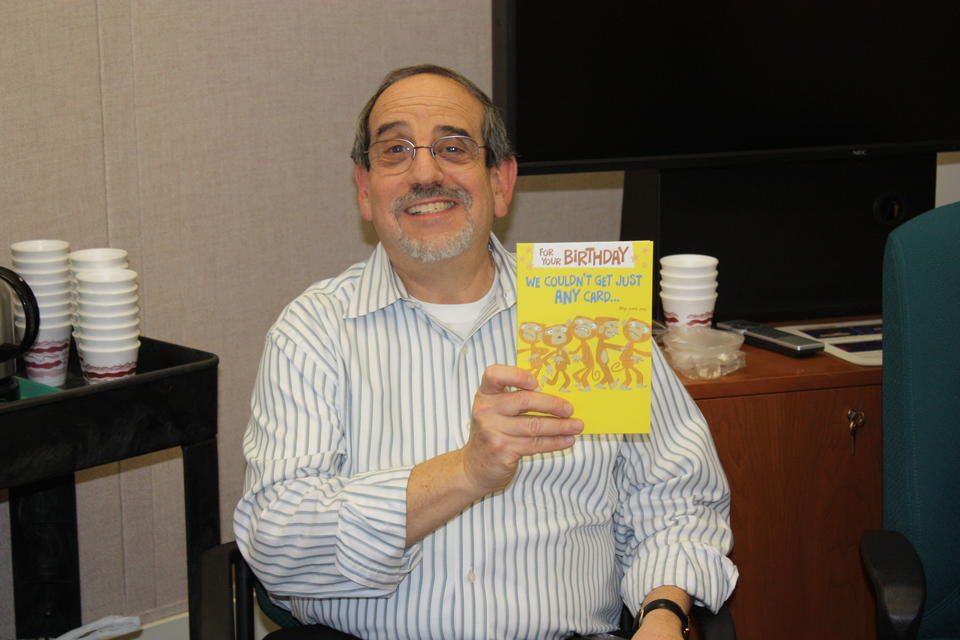 Harry Hertz holds humorous birthday card from staff members