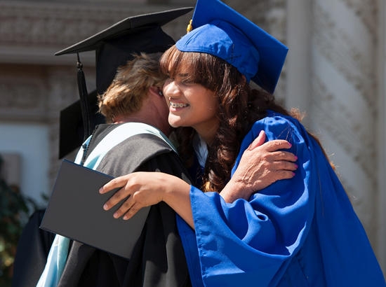 students in caps and gowns embrace