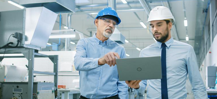 men looking at a laptop in a digital manufacturing facility